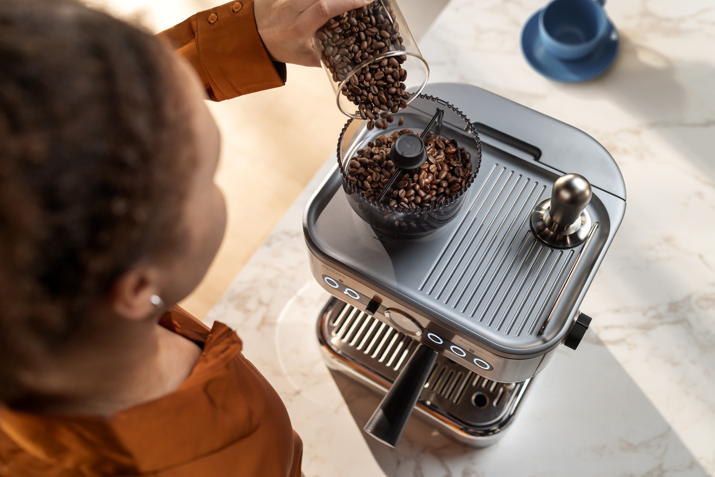 A young lady is pouring coffee bean into the Philips Barista brew coffee bean container